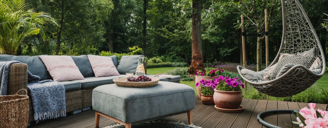 Garden patio decorated with Scandinavian wicker sofa and coffee table